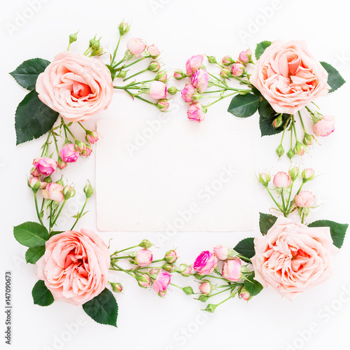 Floral frame with pink roses and paper card for calligraphy on white background. Flat lay  top view. Floral background.