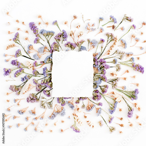 Empty white paper blank on blue and purple dried flowers frame on white background. Flat lay, top view