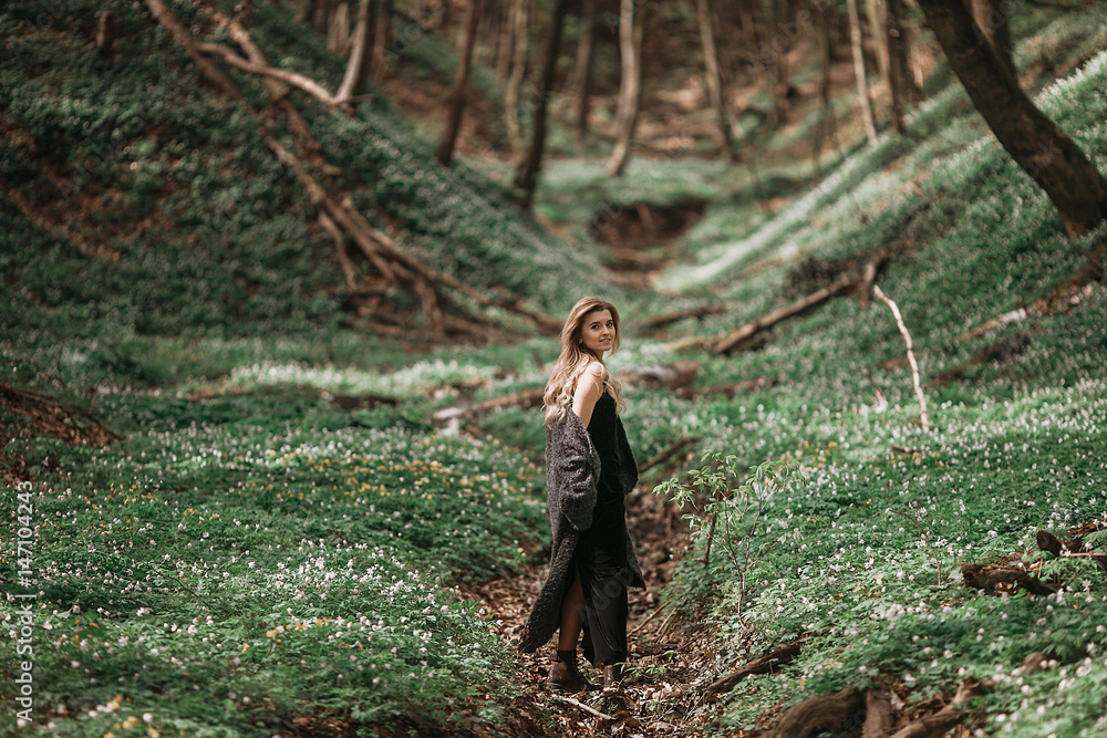 Pretty blonde woman walks in black coat on the green grass Pretty blonde woman walks in black coat on the green grass
