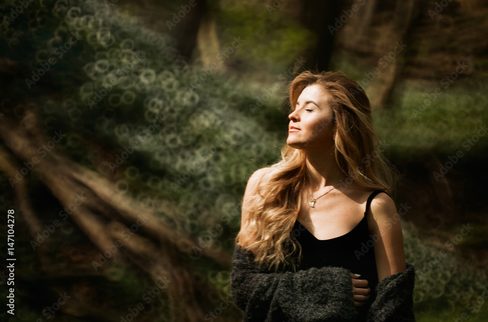 Blurred picture of stunning blonde facing the sun in the forest Blurred picture of stunning blonde facing the sun in the forest