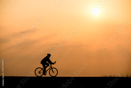 Silhouette of cyclist on sunset background