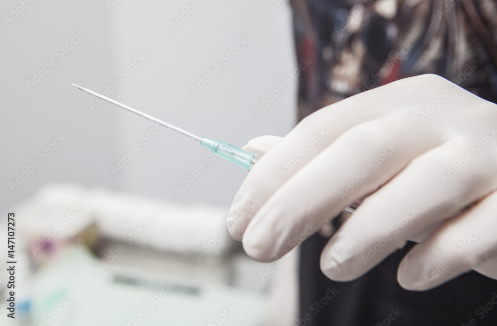 Professional holding the needle cannula on hand for piercing Stock