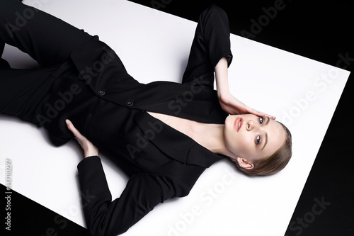 High fashion portrait of young elegant woman in black suit.
