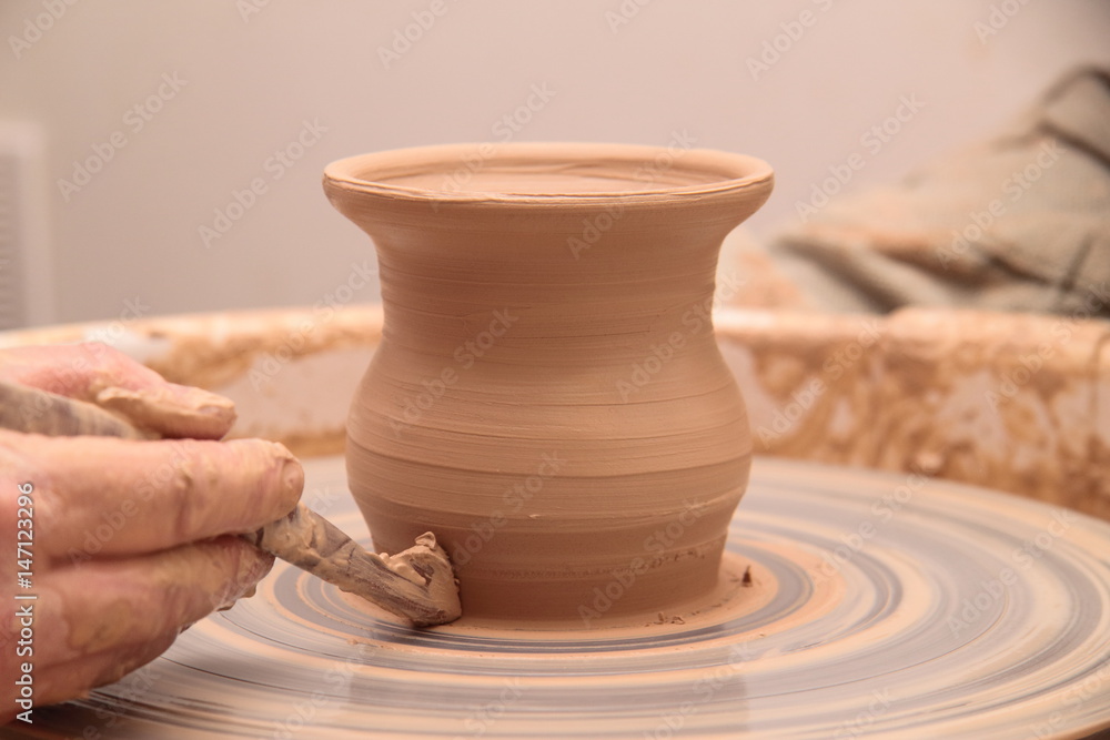 Hands of a potter, creating an earthen jar on pottery wheel. Hands of a potter, creating an earthen jar on pottery wheel.