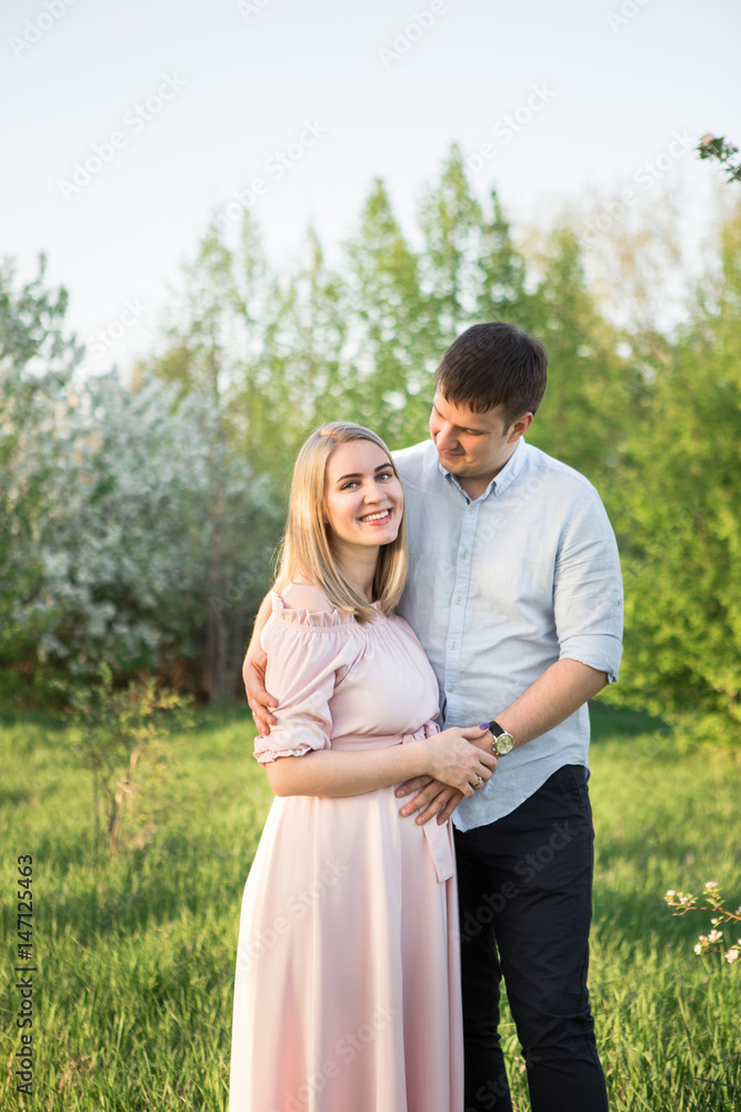 Young parents in a spring park at sunset. Pregnant woman. Young parents in a spring park at sunset. Pregnant woman.