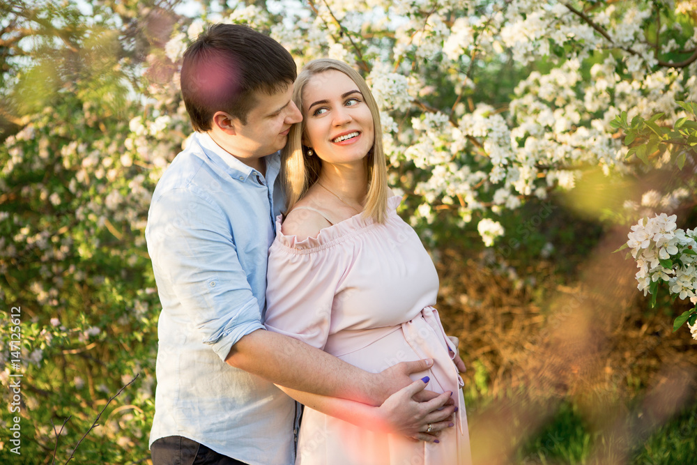 Young parents in a spring park at sunset. Pregnant woman. Young parents in a spring park at sunset. Pregnant woman.