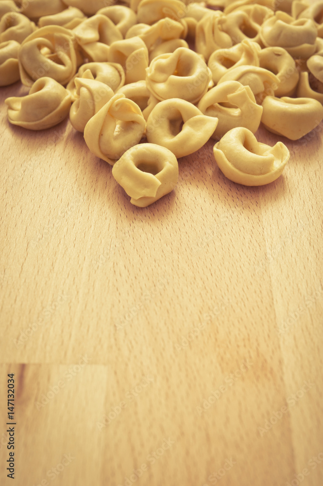 dry raw pasta tortellini on wood rustic background with copy space 