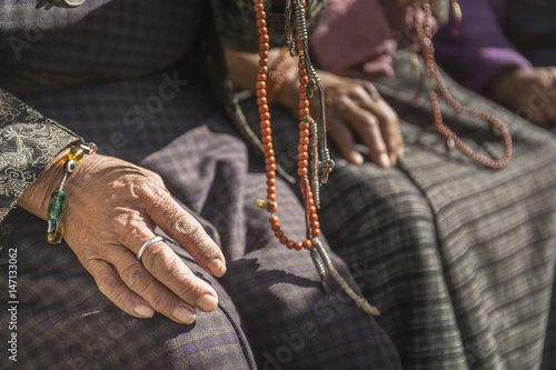 Hands of old buddhist devotee holding prayer beads photo