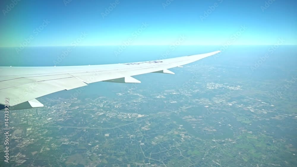 Passenger Plane In Flight. Airplane's wing flying above the colorful land. Airplane window view showing wing of the plane flying over land. Passenger Plane In Flight. Airplane's wing flying above the colorful land. Airplane window view showing wing of the plane flying over land.