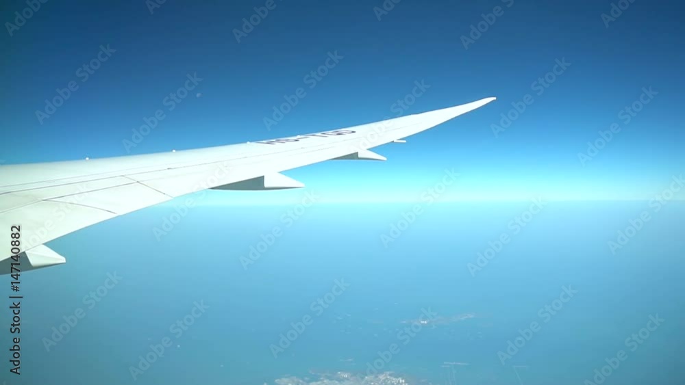 Passenger Plane In Flight. Airplane's wing flying above the colorful land. Airplane window view showing wing of the plane flying over land. Passenger Plane In Flight. Airplane's wing flying above the colorful land. Airplane window view showing wing of the plane flying over land.