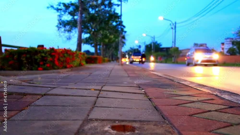 sidewalk and blur car move traveling on the country road in sunset light. camera pan down sidewalk and blur car move traveling on the country road in sunset light. camera pan down