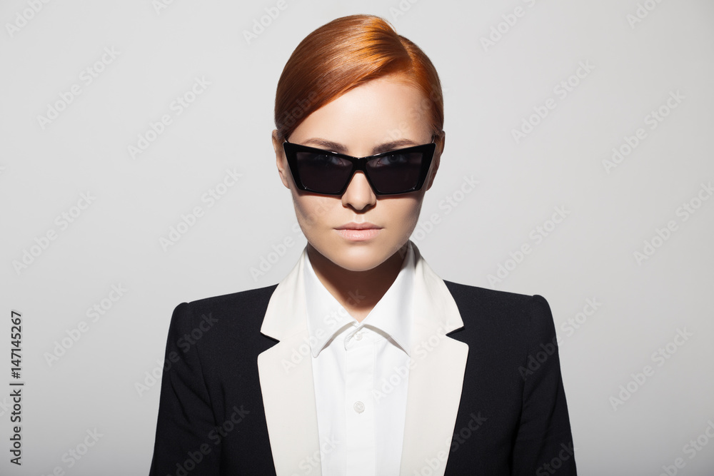 Fashion portrait of serious woman dressed as a secret agent or spy. Gray background. Fashion portrait of serious woman dressed as a secret agent or spy. Gray background.