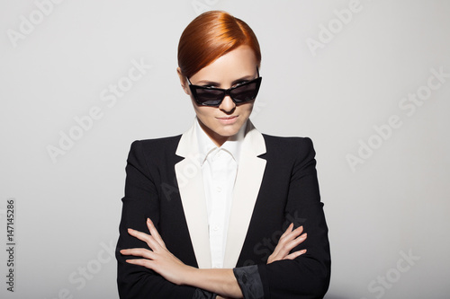 Fashion portrait of serious woman dressed as a secret agent or spy. Gray background.