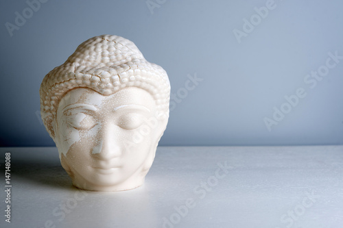 Buddha face. Buddha statue made of white marble with free space for text. Concept of peace, calm and tranquility. Buddhist artifact for Zen style interior decor.