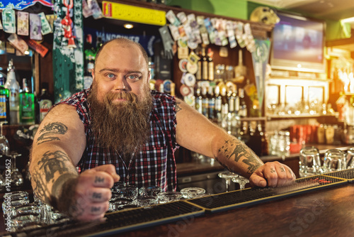 Happy bearded man standing at counter near drinks