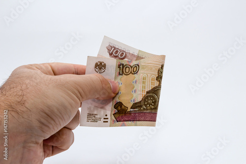 A close up photo of a Caucasian male hand holding a 100 russian ruble note photo