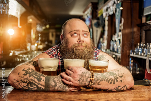 Foto Pensive male embracing mugs of alcohol beverage