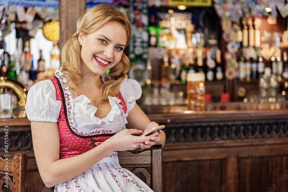 Cheerful female watching at cellphone in boozer