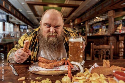 Fotografie Man eating frankfurters in pub