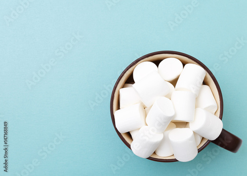 Sweet marshmallow in cup, candy on blue background, top view flat lay. Isolated minimal concept above decoration, view white marshmallow, food background
