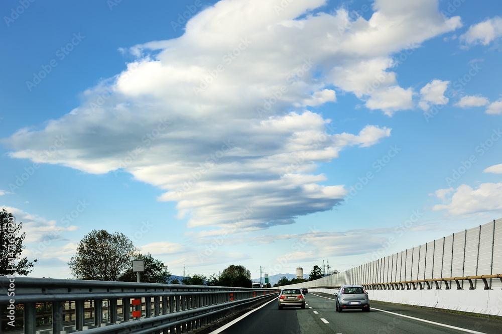 Highway road, cars, guardrail, sky and clouds