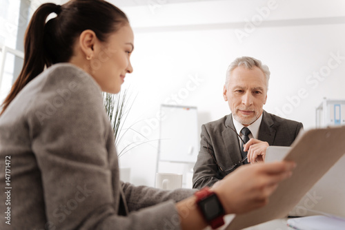 Positive delighted male person looking at folder with documents