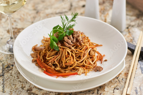 Canvas Print Flat egg noodles with pork slices served on white plate with white garlic and re