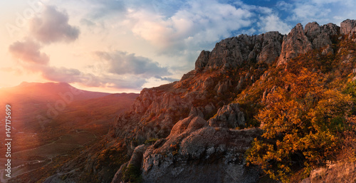 Crimean autumn mountain landscape with a setting sun, backlit orange trees and a beautiful cloudy sky.Demerdzhi mountain range is considered to be one of the most picturesque in the Crimea. Russia. © Vlad Sokolovsky