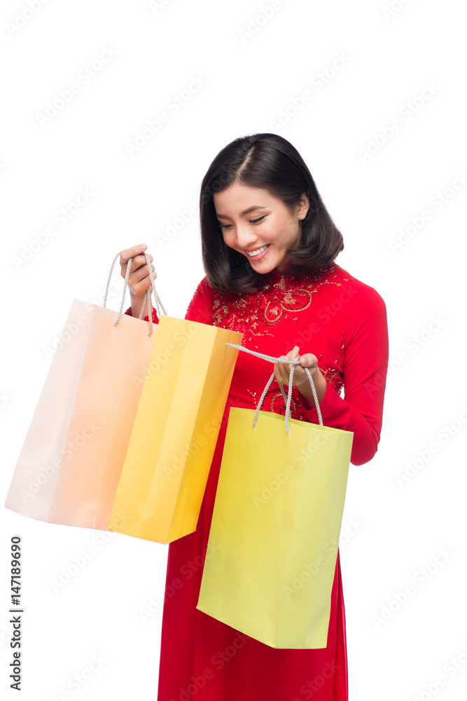 Charming Vietnamese Woman in Red Ao Dai Traditional Dress holding Shopping Bags.