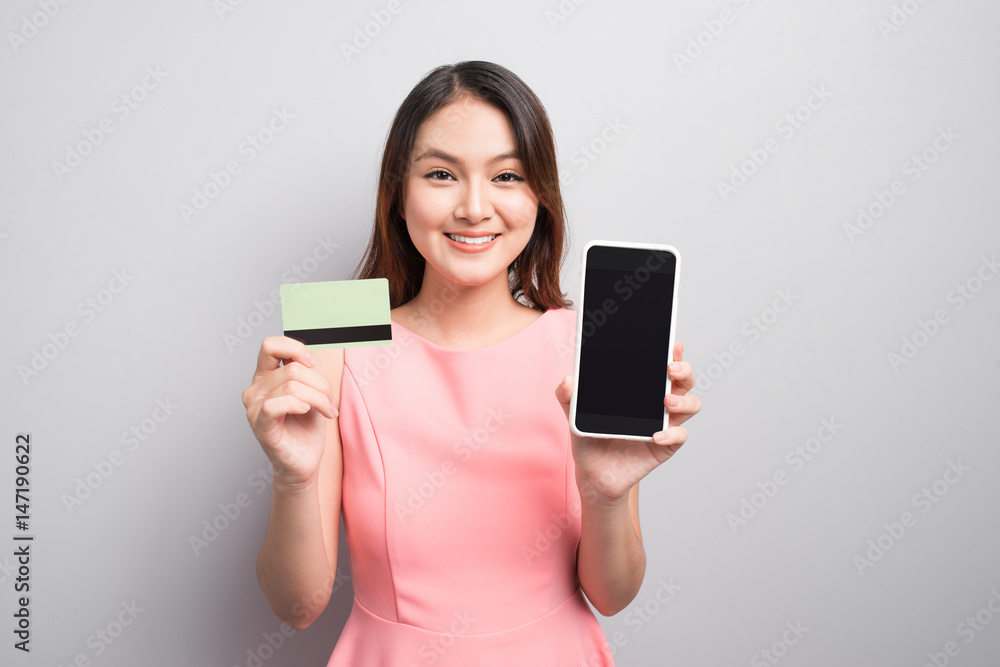 Charming asian woman hand holding smartphone and show credit card. Presenting your product. Charming asian woman hand holding smartphone and show credit card. Presenting your product.