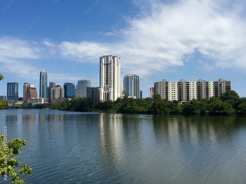 Landscape view of Austin Texas skyline from Lady Bird Lake, Colorado river filling bottom half, background, sunshine sky above, room for text
