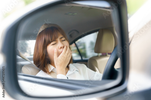 Closeup portrait sleepy, tired young woman driving her car after long hour trip in mirror, Sleep deprivation, accident concept.