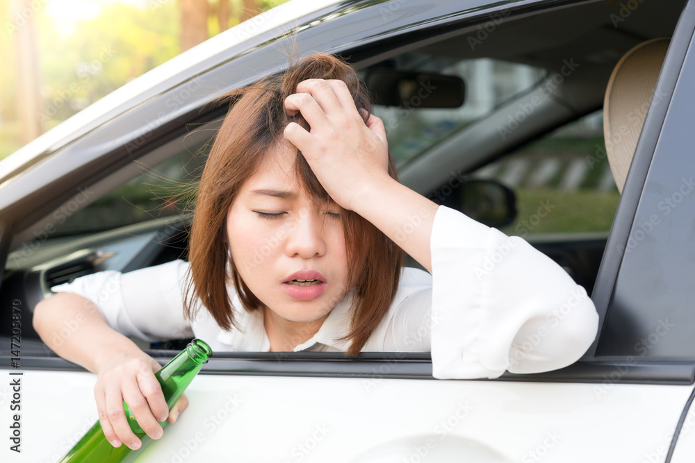 Drunk asian woman feels dizzy after too much drinking alcohol and driving car.