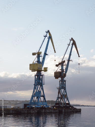 cranes at harbor against sky