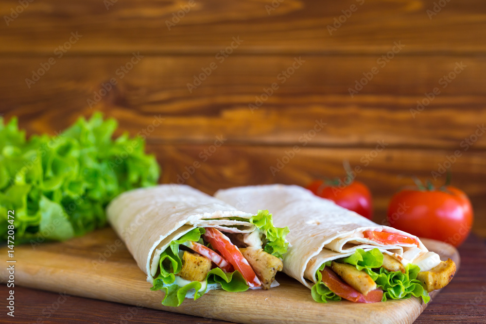 Pita bread with chicken, greens, tomatoes on a wooden background. Sandwich