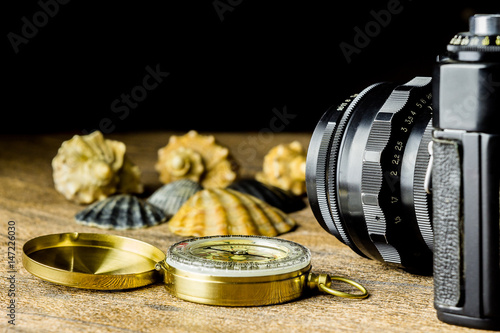 Old fotocamera with sea shells and compass on the brown wooden table photo