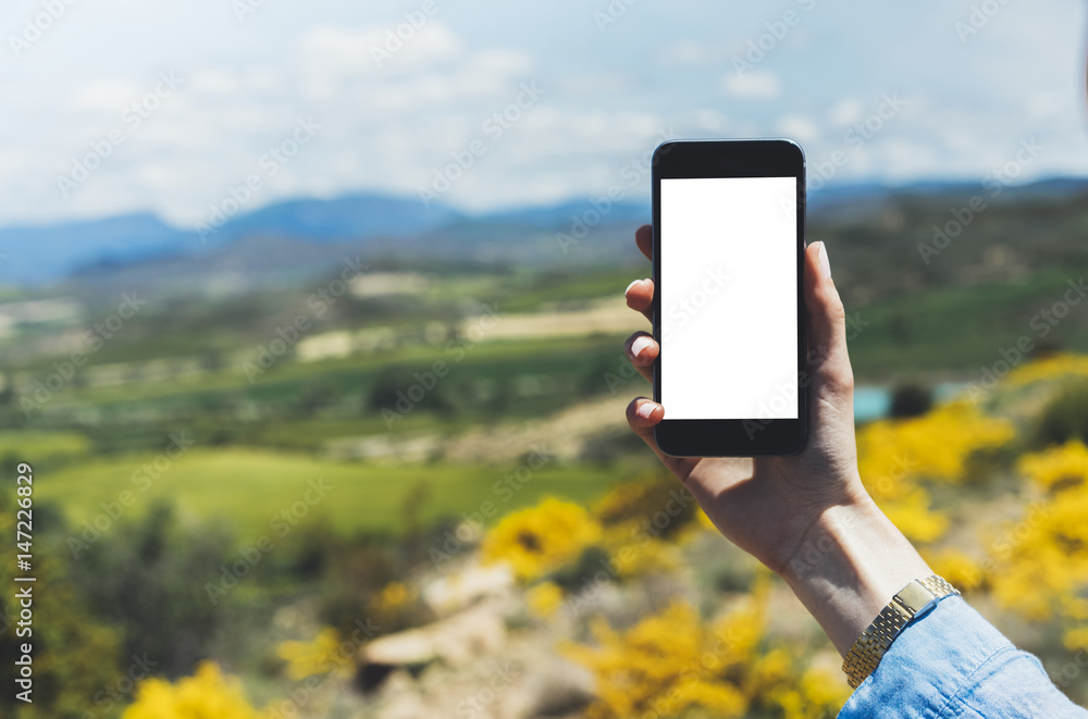 Hipster photograph on smart phone gadget mobile, mock up of blank screen. Traveler hold and using in hand mobile on background mountain landscape horizon. Tourist look map on trip, lifestyle concept