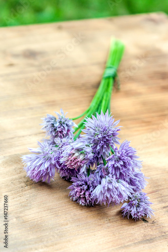 Flower chives tied in a snop on a natural wooden cutting board