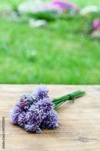 Flower chives tied in a snop on a natural wooden cutting board