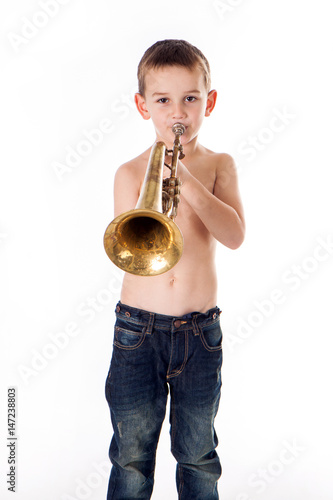 young boy blowing into a trumpet against white background