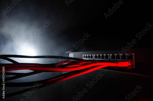 Network switch and ethernet cables, symbol of global communications. Colored network cables on dark background with lights and smoke. Selective focus