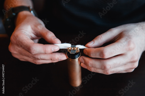 master installs cotton wool to refuel an electronic cigarette.Vape. vaping device