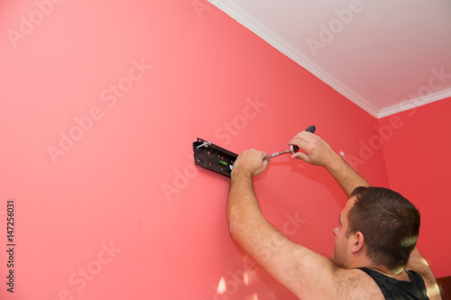 the man is installing the TV wall mount red carrot color of wall photo