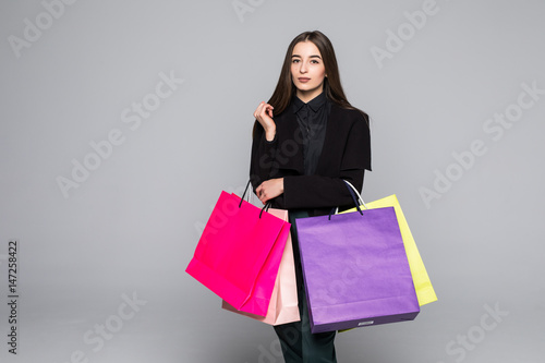 Portrait of young happy smiling woman with shopping bags on grey