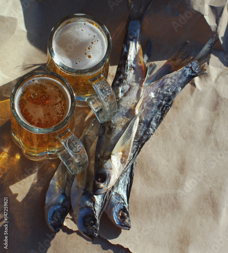 Two glasses of beer, salty fish on paper. Beer and snack to beer. photo