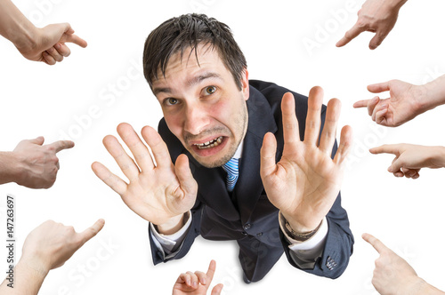 Many hands are pointing and blame stressed man. Isolated on white background. photo