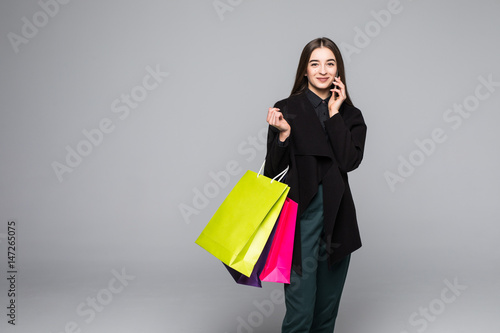 Trendy modern shopping woman carrying bag typing on the smartphone.