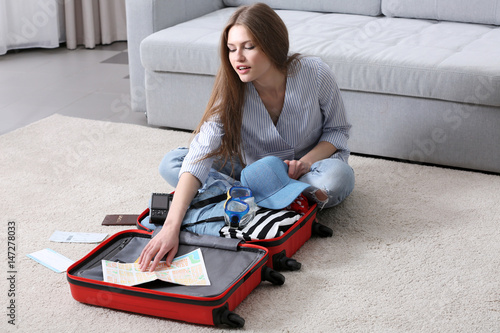 Woman packing her red suitc...