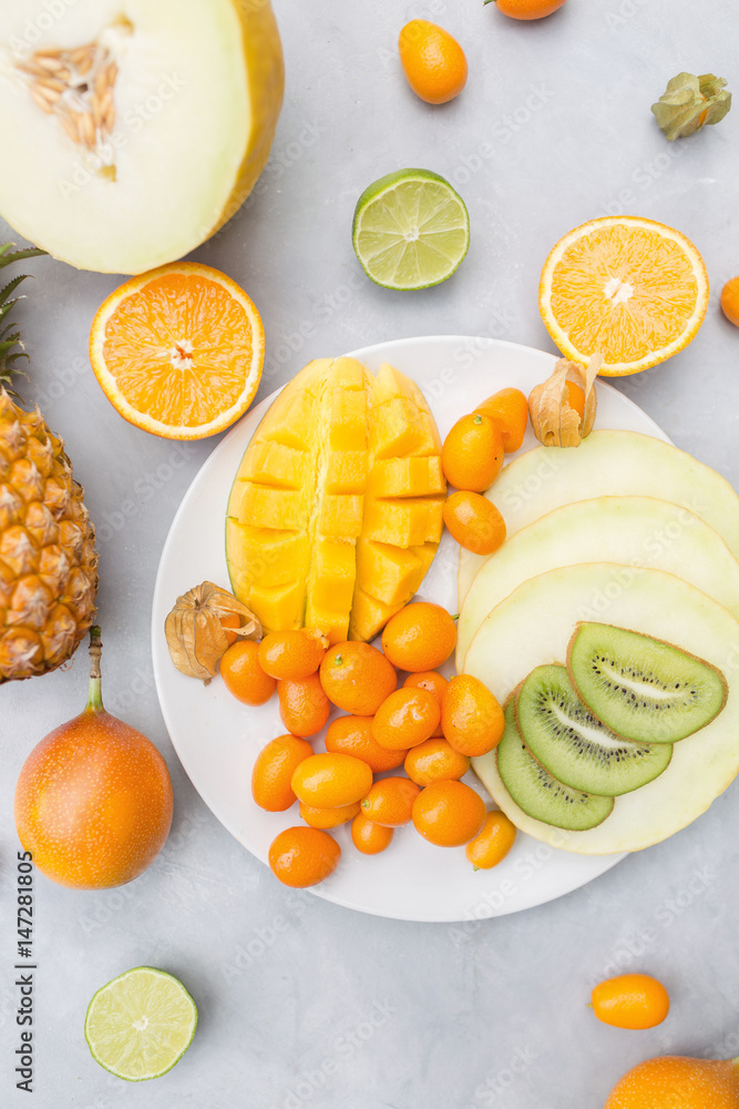 Pineapple, mango, granadilla, kumquat, fizalis, melon, orange on a gray background. Exotic fruits Pineapple, mango, granadilla, kumquat, fizalis, melon, orange on a gray background. Exotic fruits