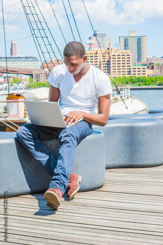 Young African American Man traveling, working on laptop computer in New York